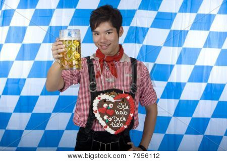 Giovane uomo vestito in pantaloni di pelle (lederhose) tenendo un stein di birra Oktoberfest nella macchina fotografica.
