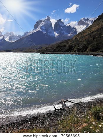 A strong wind blows turquoise waves on the lake, grand cliffs of Los Kuernos covered with snow and ice.  Magic beauty of Lake Pehoe
