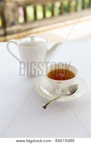 drinks, relaxation and tea party concept - tea-set of cup, pot, spoon and saucer at teahouse
