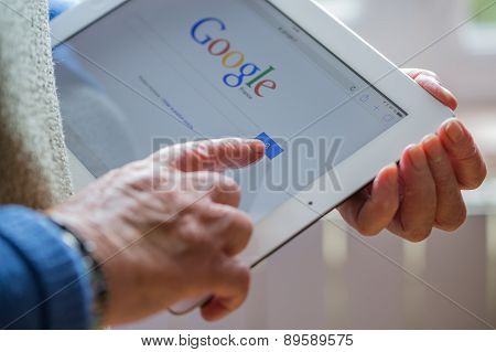 Paris, France - April 27, 2015: Senior Woman Using Tablet With Google Search Home Page On A Ipad Scr