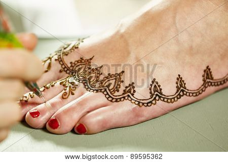 Mehendi. Master applying henna on model's leg