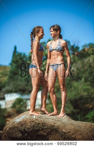 two young girls on stones on a beach