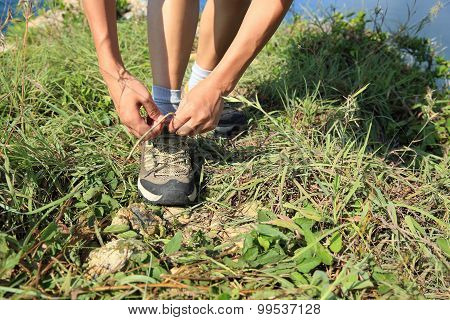 woman hands tying shoelace on seaside mountian grass