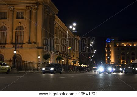 Night scene of cars driving by in the area between Hilton Athenee Palace hotel and the National Muse