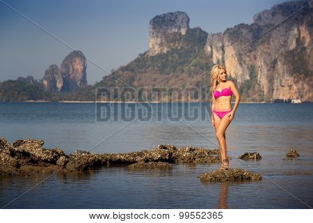 Blonde Girl In Swimsuit Stand On Sea Stones