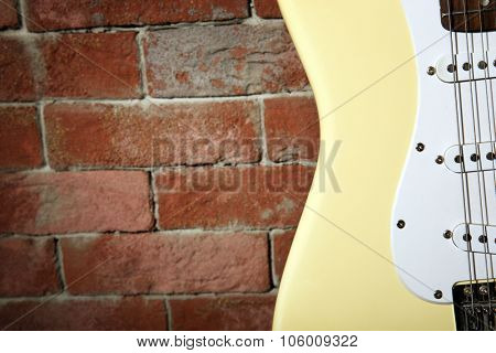 Guitar's body on brick wall background, close up
