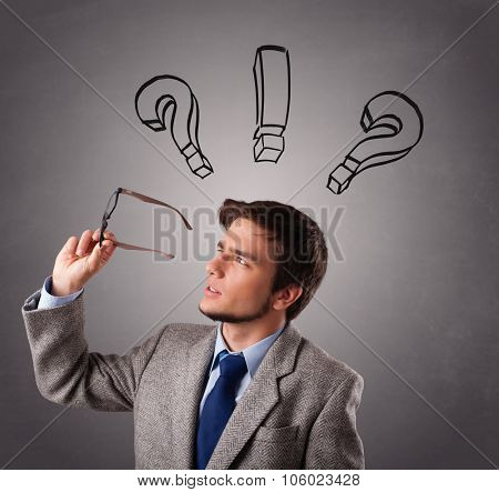 Young man standing and thinking with question marks overhead