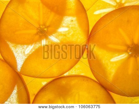 background of back lit ripe kaki persimon slices arranged
