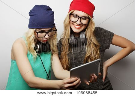two hipster girls friends use digital tablet, studio shot over gray vackground