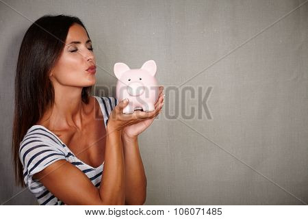 Charismatic Young Woman Kissing A Piggy Bank