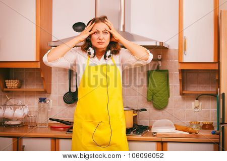 Housewife With Earphones In Kitchen