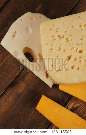 various types of fresh raw aged delicatessen cheese on wooden table cheddar edam swiss