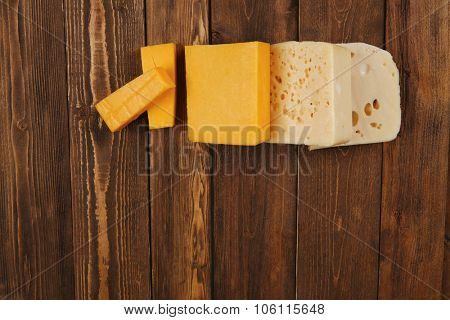 various types of fresh raw aged delicatessen cheese on wooden table cheddar edam swiss