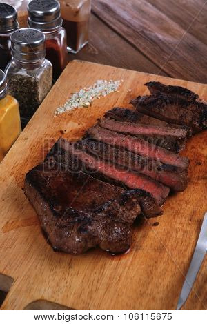 fresh roast red beef meat fillet mignon cutted on wooden plate with vintage fork many different kinds of dry spice over table