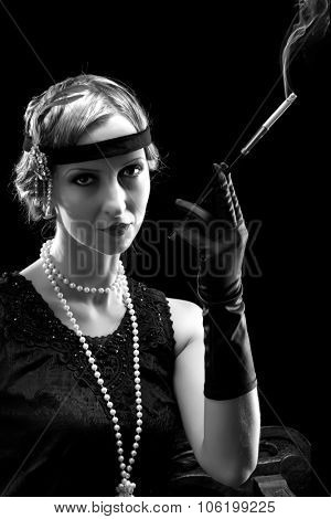 Woman in flapper dress in twenties style smoking a cigarette