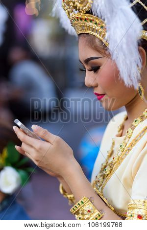 BANGKOK, THAILAND, February 17, 2015 : A Thai lady traditional dancer is checking her smartphone before the show celebrating the new Krung Kasem floating market in Bangkok, Thailand