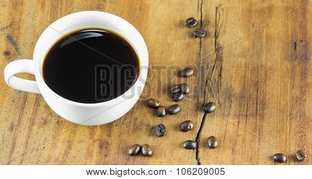 A Cup Of Coffee And Coffee Beans On Wood Background, Warm Toning, Selective Focus