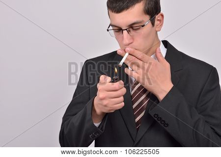 Young Man Dressed In Tuxedo Lighting Cigarette In Studio