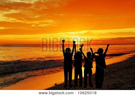 Børn ved stranden ser på sunset