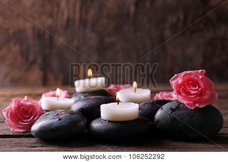 Tenderness relaxing composition with pebbles, roses and candles on wooden background