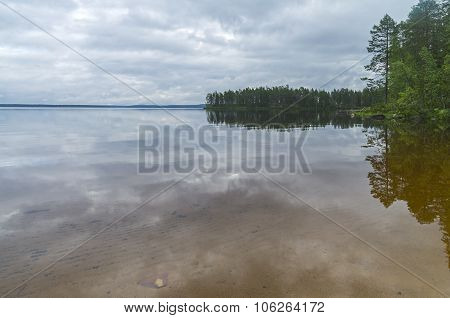 Clouds And Coastal Forest Are Reflected In The Clear Lake