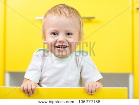 Kid sitting inside yellow opened kitchen box