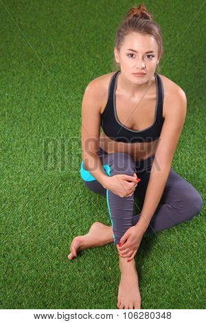 Beautiful young woman relaxing after exerscises on the grass 