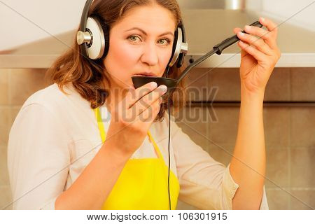 Housewife With Earphones In Kitchen