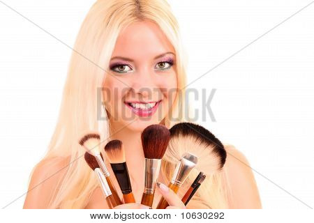 Giovane e bella donna bionda con molti pennelli su bianco e luminoso make-up