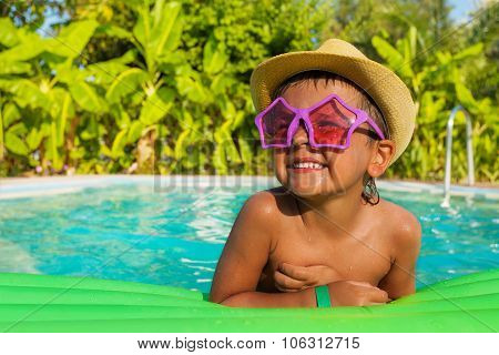 Happy boy in shaped sunglasses on green airbed
