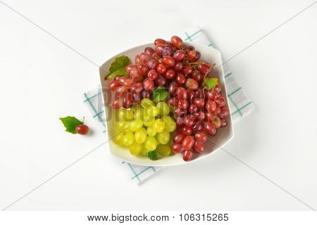 bowl of red and white grapes on checkered dishtowel