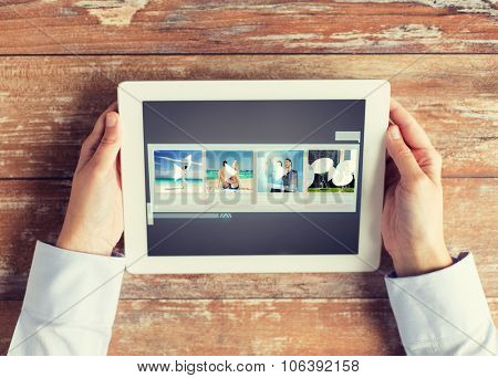 people, multimedia and technology concept - close up of hands with video gallery slideshow on tablet pc at table