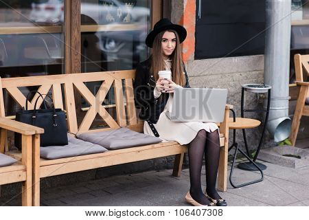 Young beautiful female enjoying coffee during work on portable laptop computer
