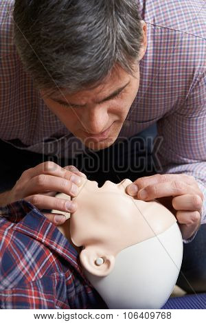 Man In First Aid Class Performing Mouth To Mouth Resuscitation On Dummy