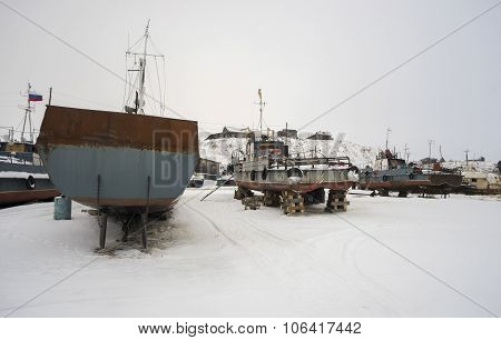 Fishing boats at rest on stands the shore.