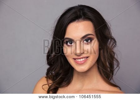 Beauty portrait of a happy woman with fresh skin looking at camera oer gray background