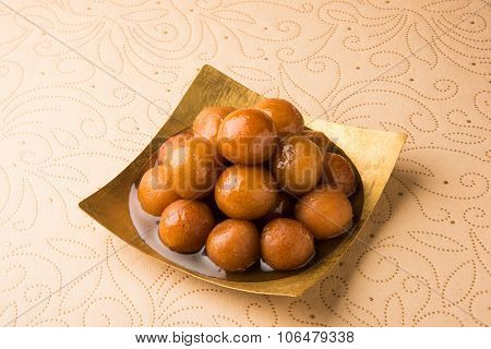 indian sweet gulab jamun in square shape brass plate, closeup and front view on cream paper with flo