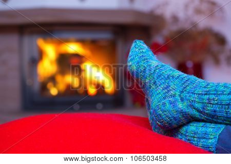 Feet in woollen blue socks by the fireplace.