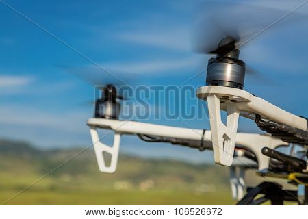 blurred spinning propellers of a hexacopter drone flying over rolling  prairie
