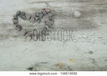 White wooden background with black marks, formed stones in image of heart