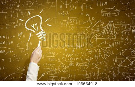 Human hand darwing light bulb as idea concept with chalk