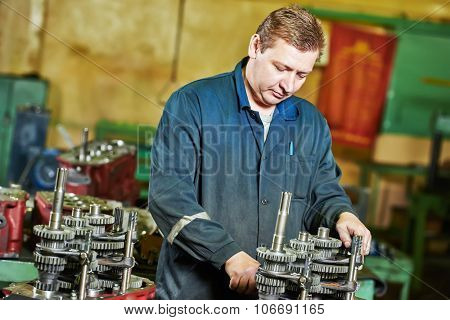 Adult experienced industrial worker assembling the reduction gear box on production line manufacturing workshop
