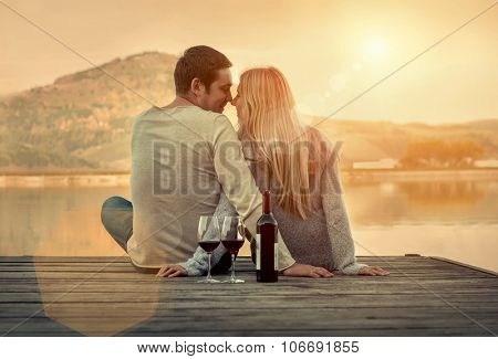 Romantic Couple sitting on the pier with red wine.