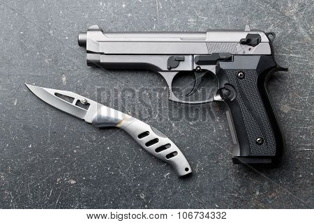handgun and knife on old background