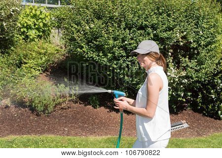 Attractive Young Woman Watering The Plants In The Garden
