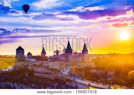 View on the castle in Kamianets-Podilskyi and red air balloon during sunset . Ukraine