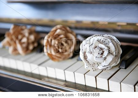 Vintage old classic piano with paper rose and musical notes on it, close up