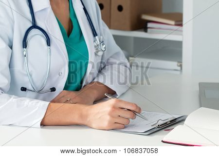 Close-up Shot Of Female Medical Doctor's Hands Filling Paient Registration Form