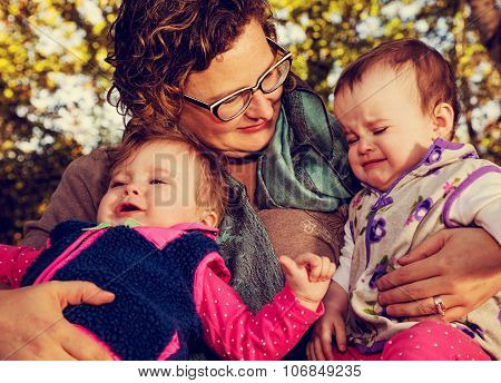 Tight Crop Of Mom Holding Crying Toddler Girls
