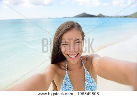 Summer vacation beach travel. Technology and people concept with smiling woman making selfie with smartphone on beach. Happy mixed race Caucasian / Asian Chinese woman taking self portrait having fun.